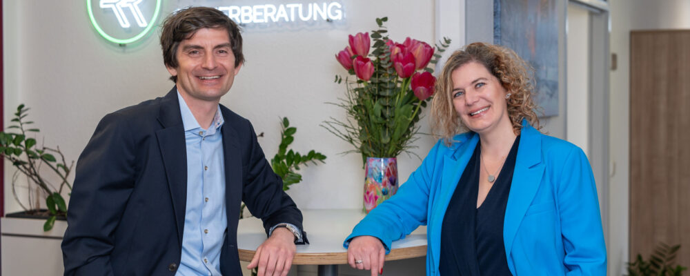 Portraitbild beider Kanzleiinhaber vor Firmenlogo