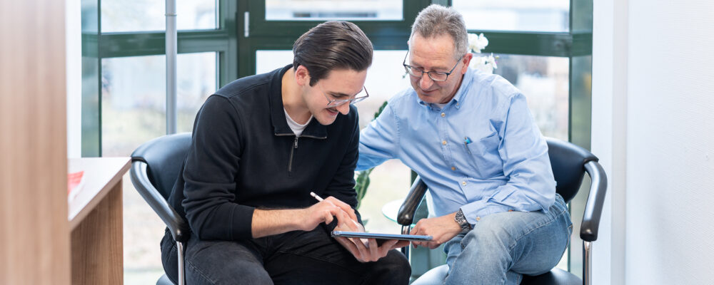 Zwei Kollegen im Gespräch schauen auf ein Tablet